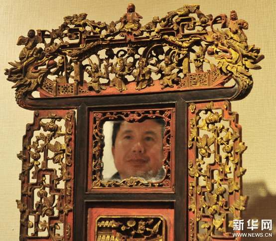 （2）2月9日，一位市民在觀看一個工藝繁復(fù)的帶鏡木雕盆架。
