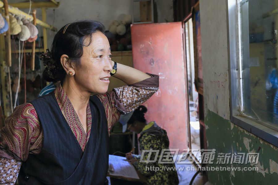 次仁拉姆，42歲，日喀則白朗縣人，是普赤的妹妹，從15歲開(kāi)始學(xué)習(xí)藏毯編織技術(shù)。1985年開(kāi)始到拉薩地毯廠從事編織工作。愛(ài)美的她時(shí)不時(shí)在工作之余照照鏡子。