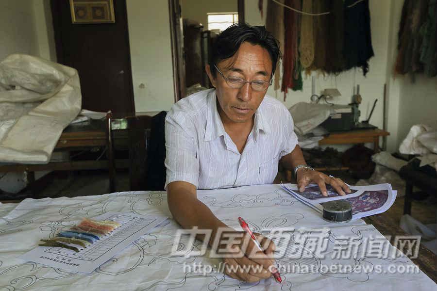 藏毯上的圖案由美工繪制。占堆，51歲，拉薩人。他在拉薩地毯廠先后從事過(guò)編織、染色、生產(chǎn)車間主管、美工等工作。退休后，又被公司聘請(qǐng)回來(lái)。他正在圖案上標(biāo)注每一部分的顏色。