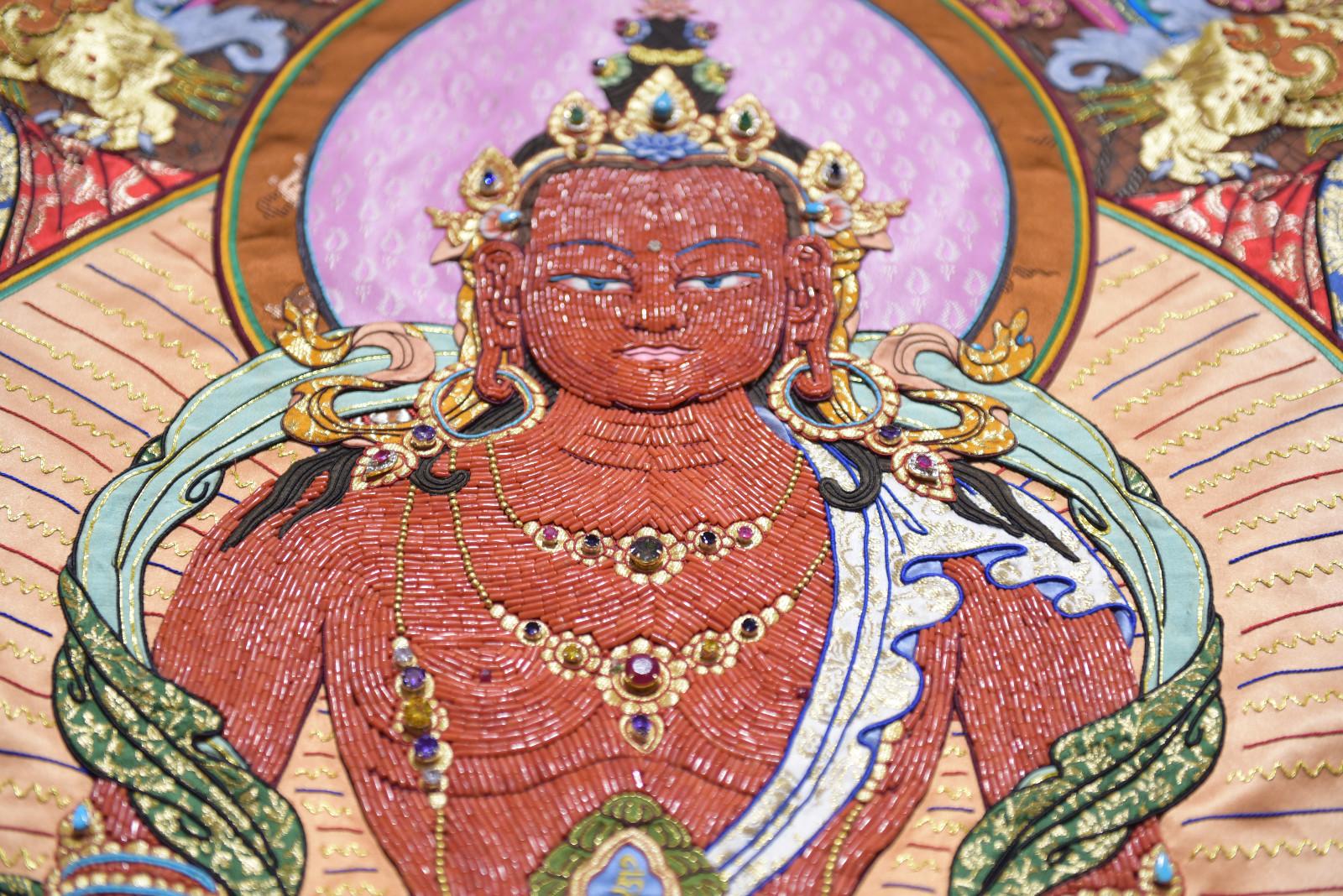 《長壽佛》刺繡流派，是丹達(dá)貢覺的精品唐卡之一。人物的主體部分，全部用了珊瑚和水晶鉆石，充分體現(xiàn)人物主題部分的立體感。