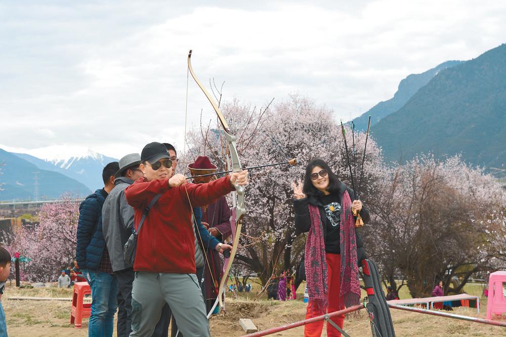 林芝桃花旅游文化節(jié)期間來自各地的游客在嘎拉桃花村體驗工布響箭。記者 史金茹 潘璐 攝