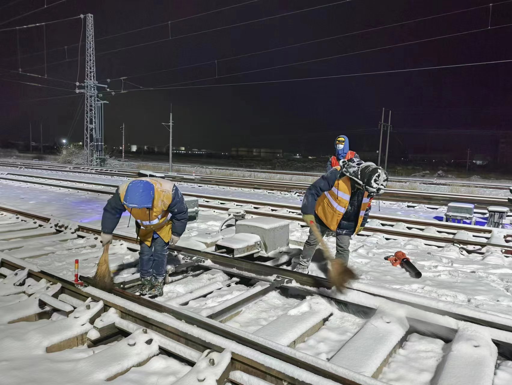 圖為鐵路職工正在進(jìn)行鐵路道岔除雪作業(yè)。